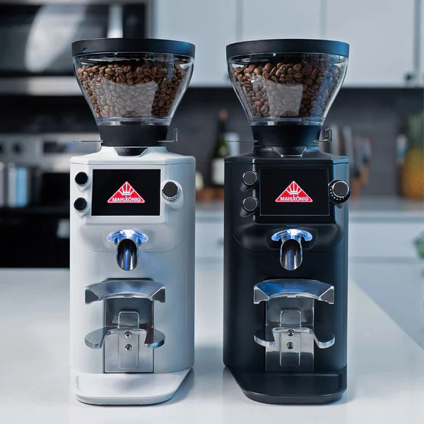 Two coffee grinders, one silver and one black, on a kitchen counter.