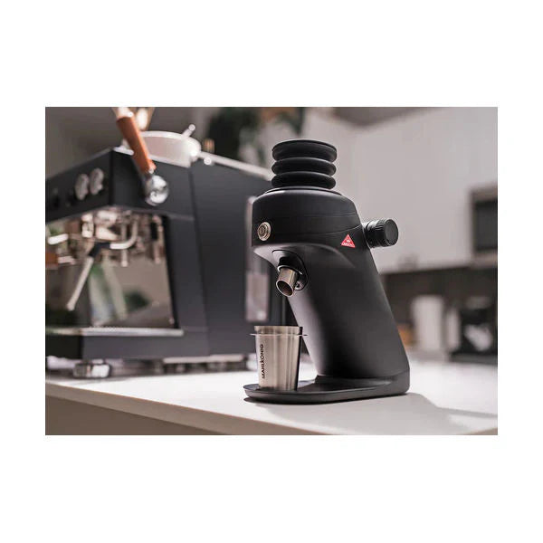 Black coffee grinder on a kitchen counter with blurred background