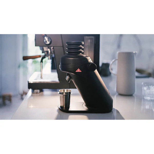 Black coffee grinder on a kitchen counter with a blurred background